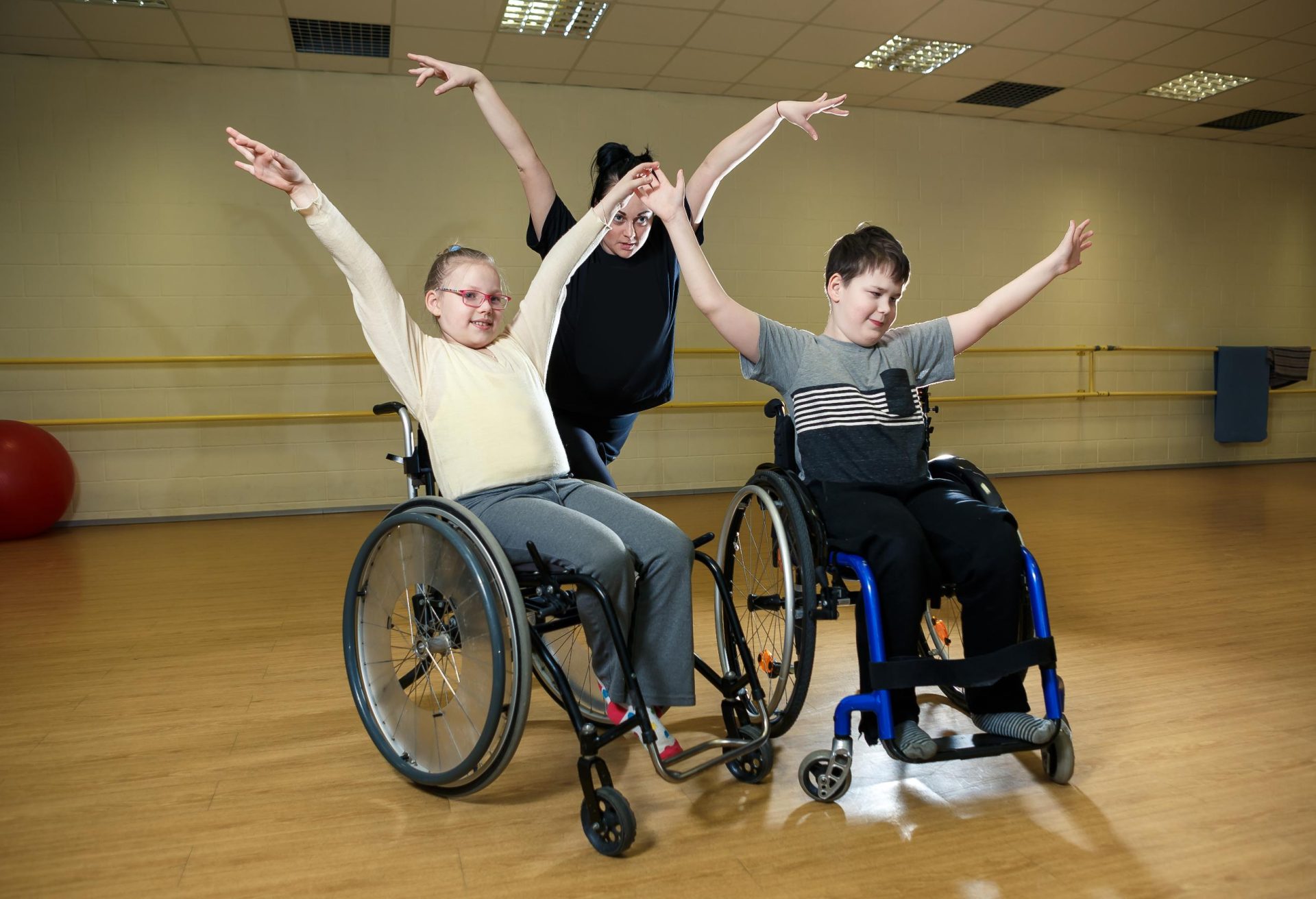 Carers doing physical exercises for 2 children on wheelchair