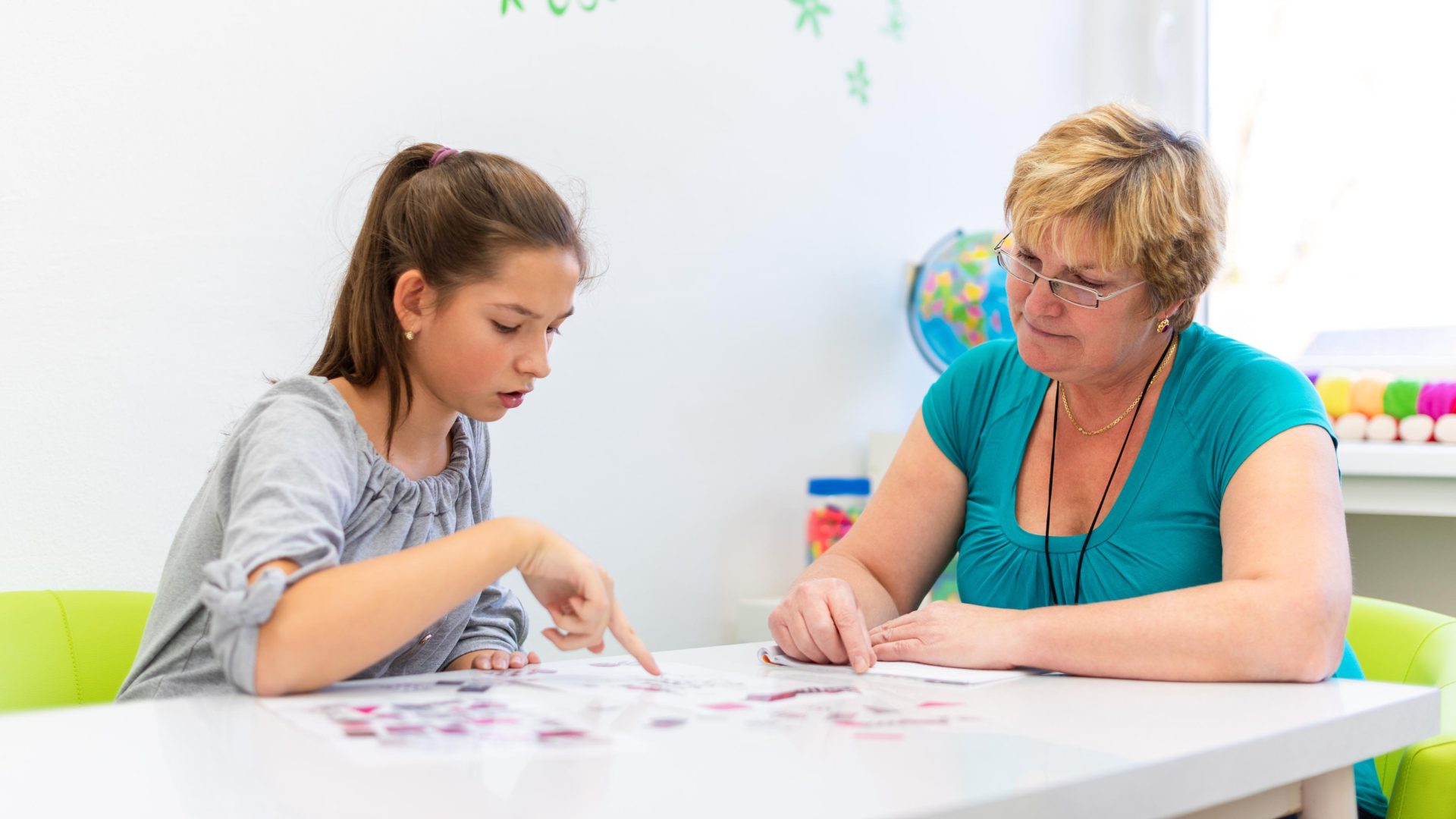 Carer helping girl who needs tailored assistance study