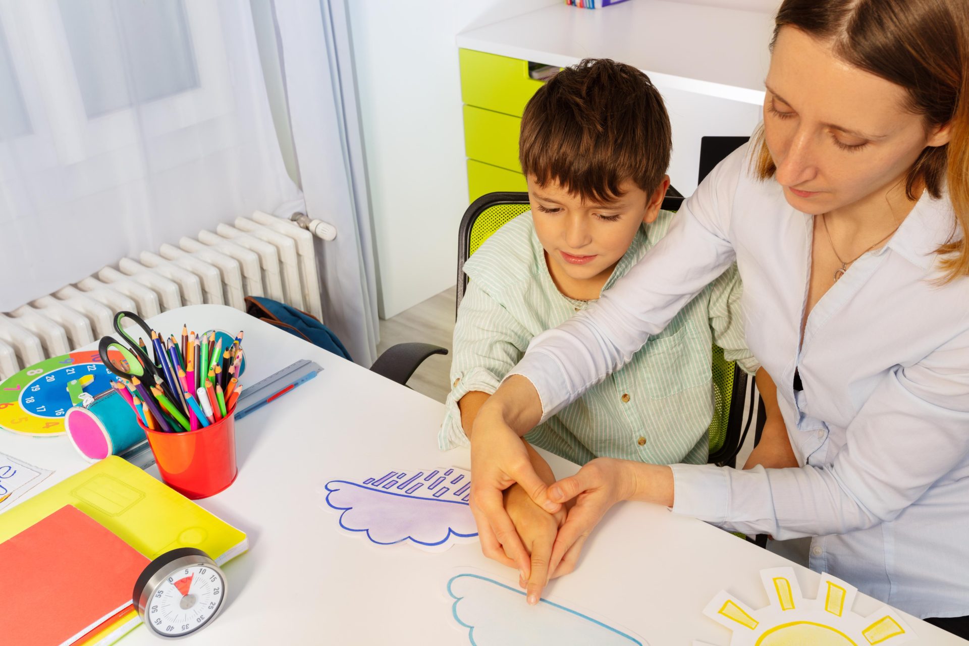 Carer helping a child with his drawings